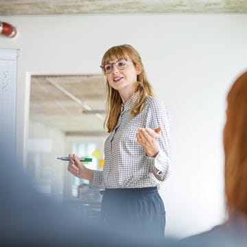 Confident businesswoman giving presentation to colleagues in office