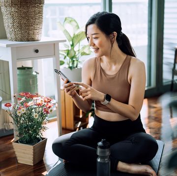 confident fitness young asian woman relaxing after exercising at home young asian female in sports wear scrolling on smartphone and resting after home work out fitness training with technology health, fitness and wellness concept