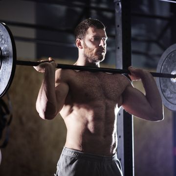 confident man lifting barbells in gym