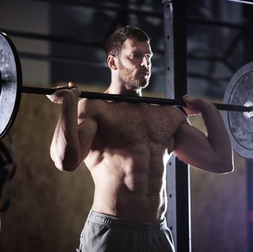 confident man lifting barbells in gym