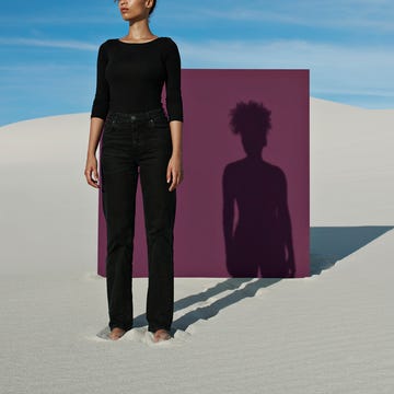 confident young fashion model standing against purple placard at white desert