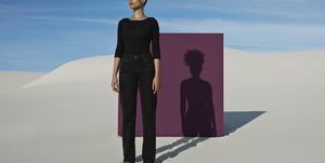 confident young fashion model standing against purple placard at white desert