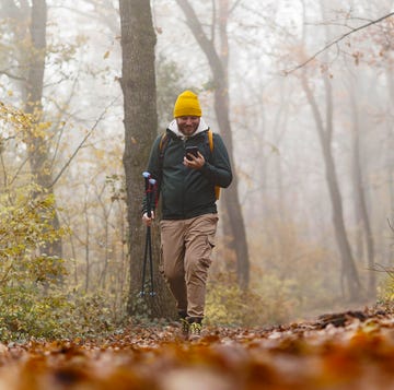 Confident young man doing walking on the mountains, he is using trekking poles and carrying a backpack, freedom and sports concept confident young man doing walking on the mountains, he is using trekking poles and carrying a backpack, freedom and sports concept