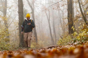 confident young man doing walking on the mountains, he is using trekking poles and carrying a backpack, freedom and sports concept