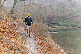 confident young man doing walking on the mountains, he is using trekking poles and carrying a backpack, freedom and sports concept