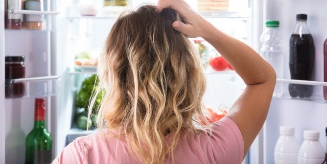 Confused Woman Looking In Open Refrigerator
