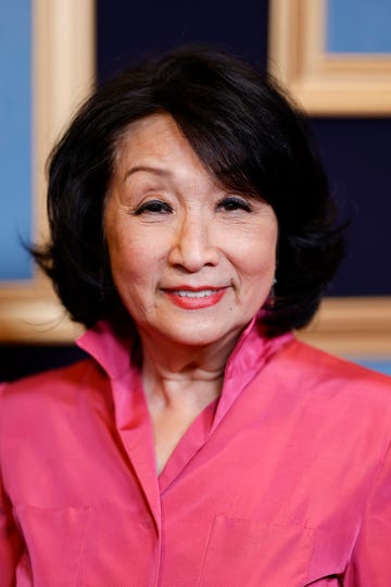 connie chung smiles at the camera, she wears a pink collared blouse