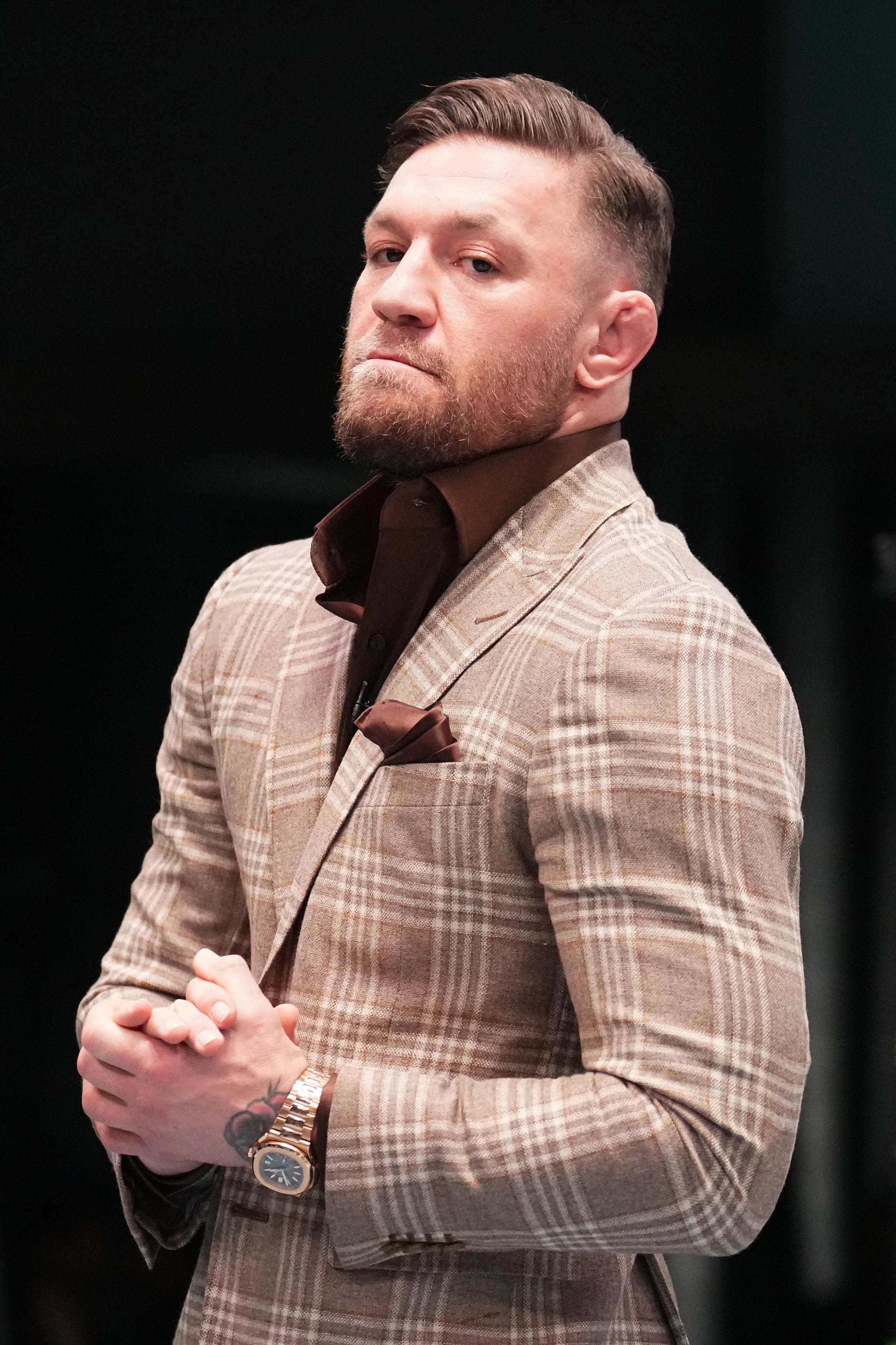 conor mcgregor looking toward the camera with his hands clasped together