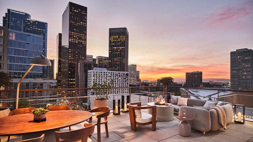 rooftop terrace with city skyline at sunset featuring a dining area and lounge