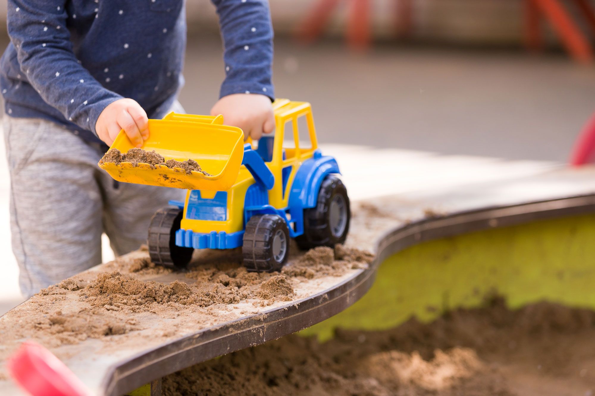 A child playing in sand with a digger
