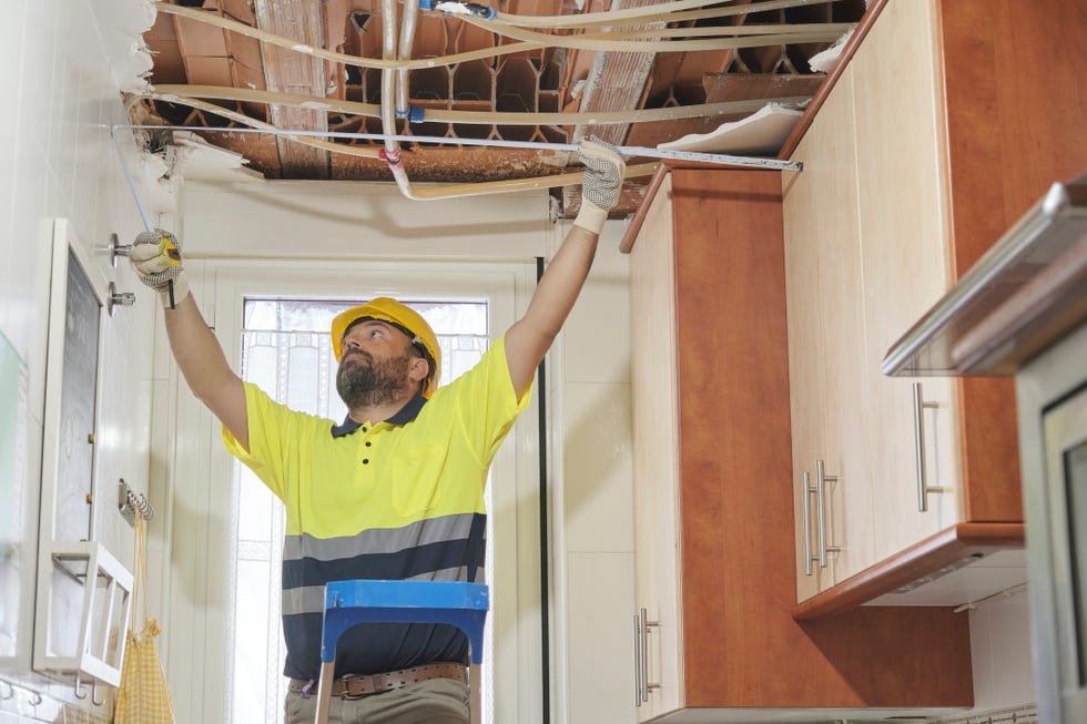 construction worker inspecting a new project taking measurements and climbing a ladder