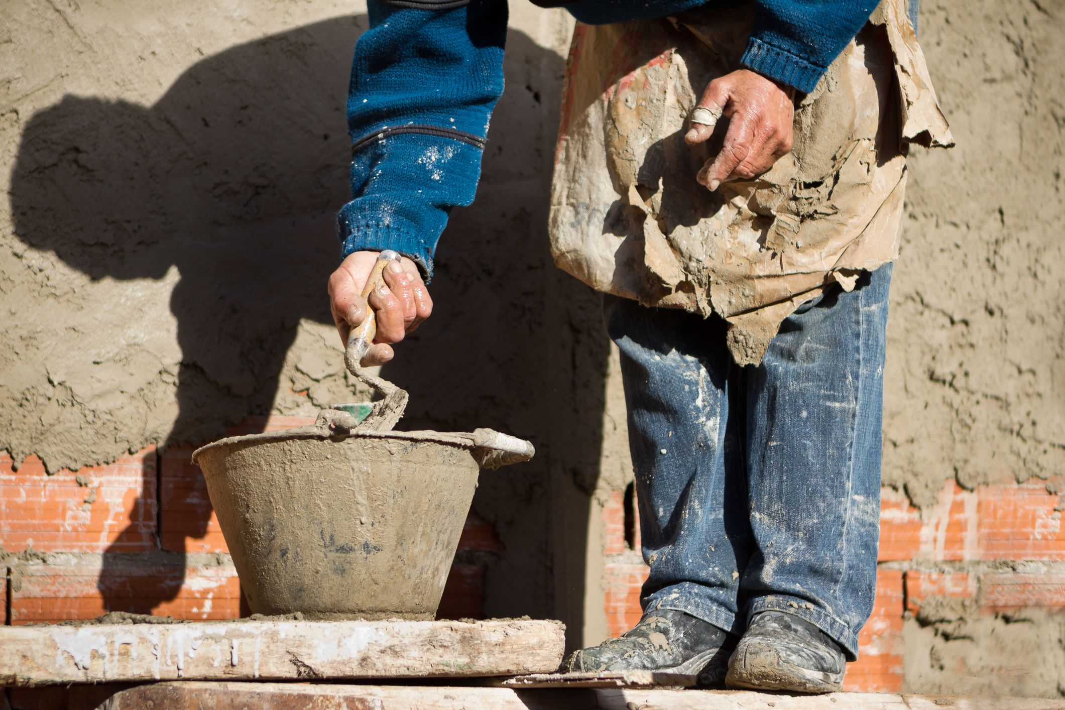 https://hips.hearstapps.com/hmg-prod/images/construction-worker-placing-cement-with-a-trowel-on-royalty-free-image-1691011711.jpg