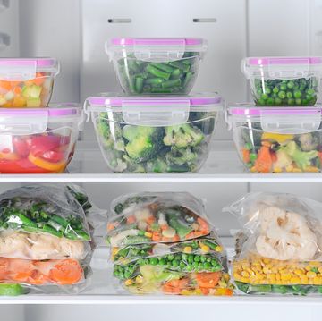 containers and plastic bags with frozen vegetables in refrigerator