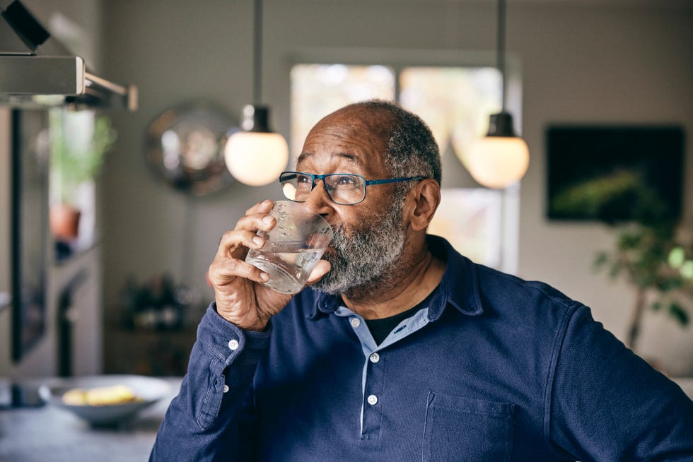 contemplative senior man drinking water at dwelling