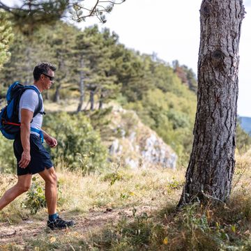 content asian mature adult hiking through a forrest