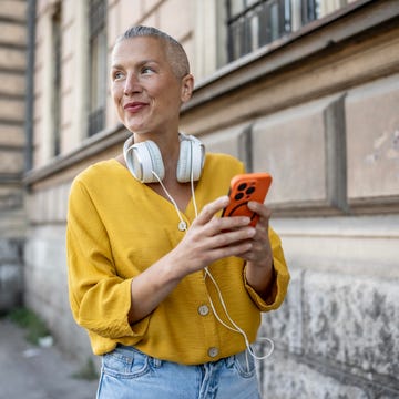 contorno ojos mujer una mujer sonr´liemientras camina por la calle consultando su teléfono móvil