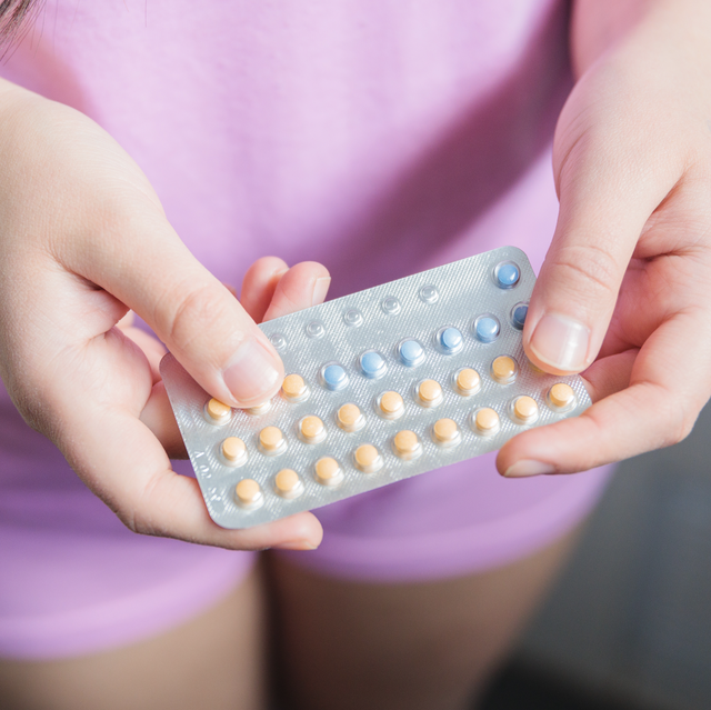 woman looks at contraceptive pill