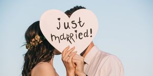 young wedding couple kissing and holding heart with just married inscription