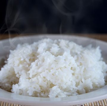 cooked hot rice in white plate with smoke in background