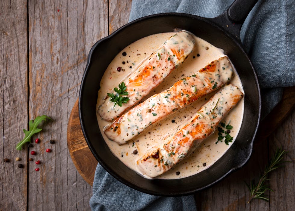 cooked salmon fish with cream sauce in frying pan