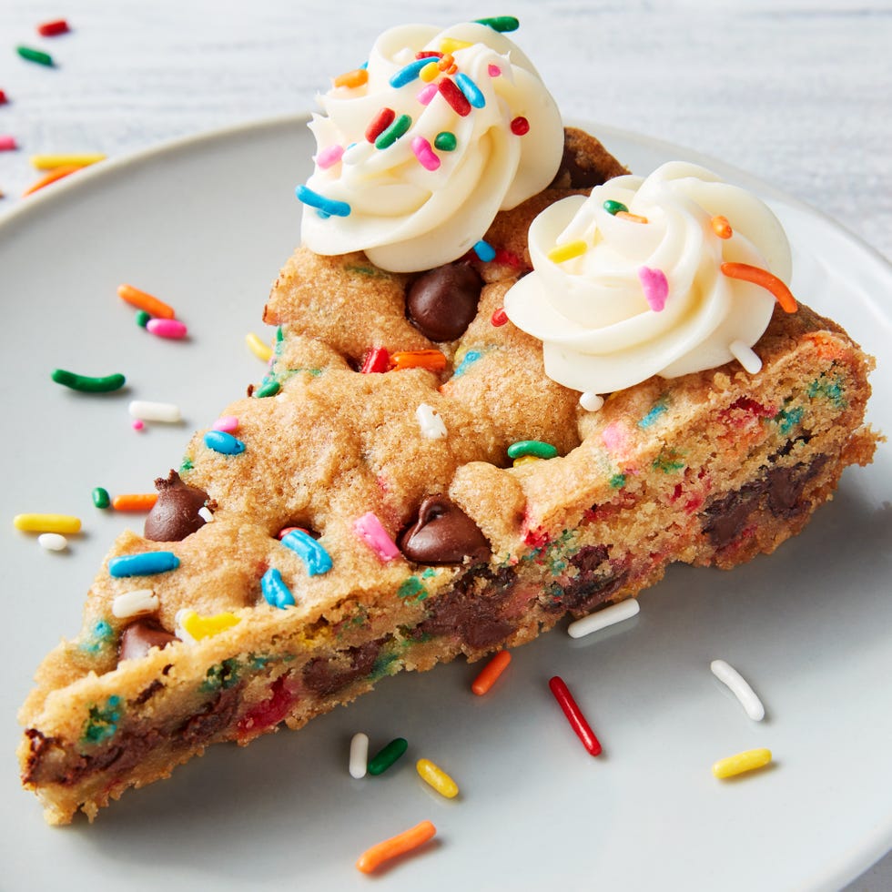 chocolate chip cookie cake topped with frosting swirls and sprinkles