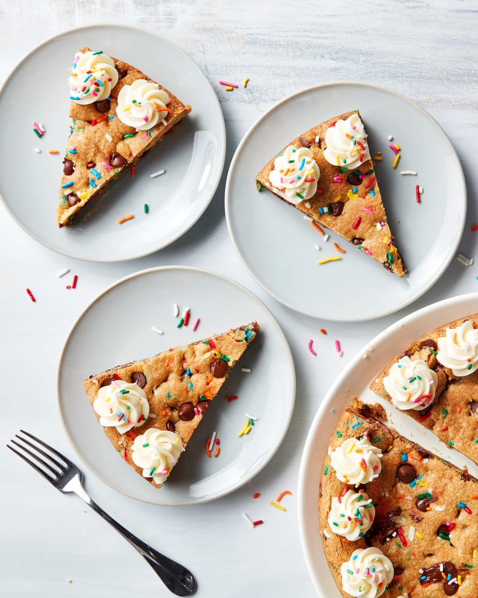 chocolate chip cookie cake topped with frosting swirls and sprinkles