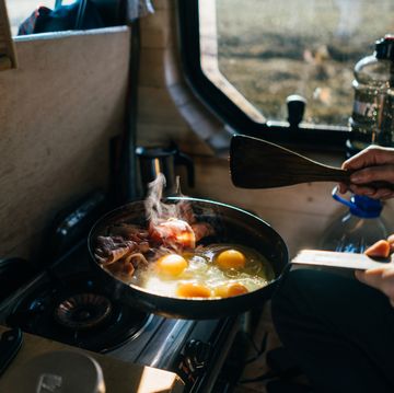cooking eggs and bacon in skillet at campsite