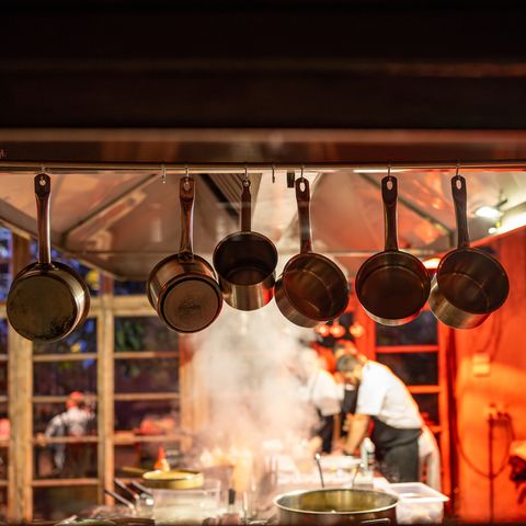 cooking in modern restaurant with open kitchen. red lighting in interior of designer cafe.