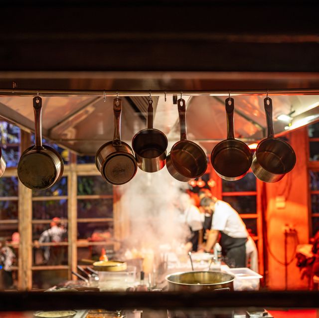 cooking in modern restaurant with open kitchen. red lighting in interior of designer cafe.