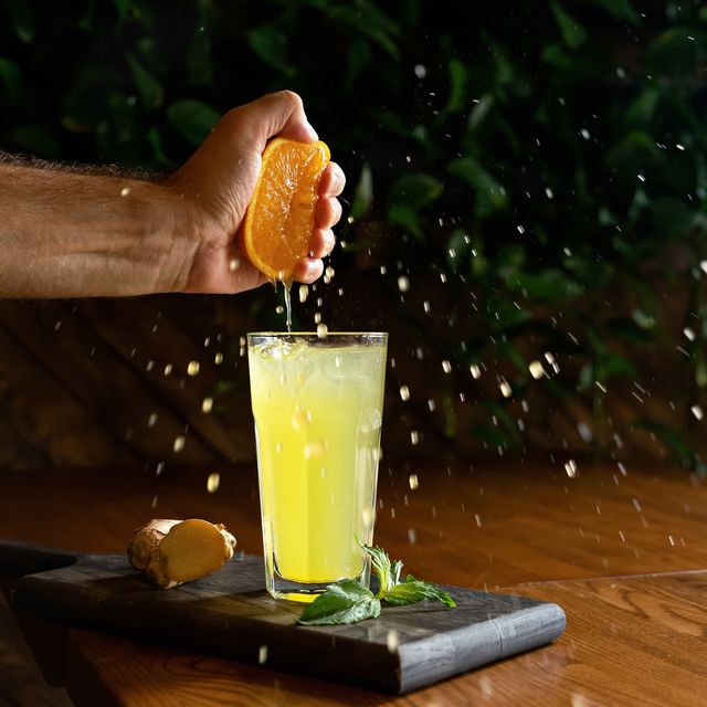 cooking process of ginger lemonade man squeezing orange juice into glass with a refreshing drink healthy fresh juice or soft drink bright colors of nature
