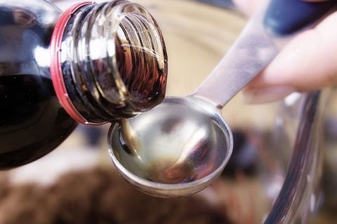 close up of medicine being poured onto a teaspoon