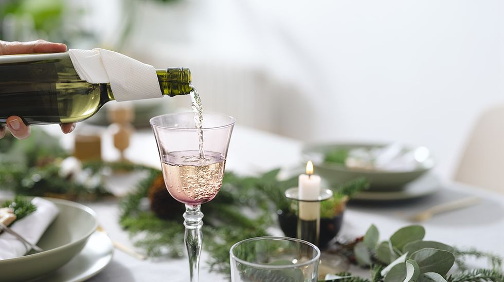 mujer rellenando una copa de vino rosa