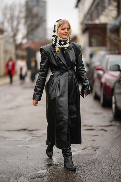 copenhagen, denmark january 31 a guest wears a white and black embroidered squared pattern wool hoodie balaclava, a black shiny leather shoulder pads buttoned long coat, black shiny leather block heels knees boots high boots, a black shiny leather shoulder bag , outside aeron , during the copenhagen fashion week autumnwinter 2023 on january 31, 2023 in copenhagen, denmark photo by edward berthelotgetty images