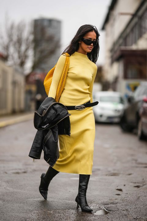 copenhagen, denmark january 31 a guest wears black sunglasses, a yellow turtleneck long sleeves wool dress, a yellow braided shiny leather large shoulder bag, a black shiny leather zipper jacket, a black shiny leather with silver buckle belt from diesel, black shiny leather pointed heels knees boots high boots , outside aeron , during the copenhagen fashion week autumnwinter 2023 on january 31, 2023 in copenhagen, denmark photo by edward berthelotgetty images