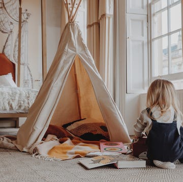 a girl sitting on the floor next to a bed with a sail