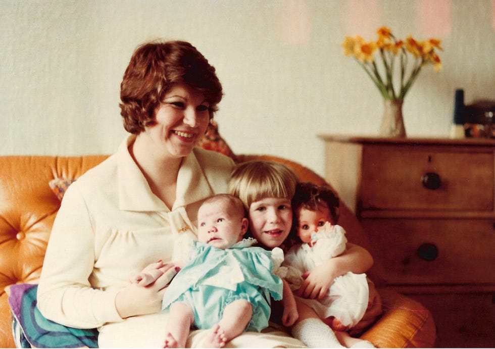 a woman seated on a sofa with two children surrounded by a cozy home environment