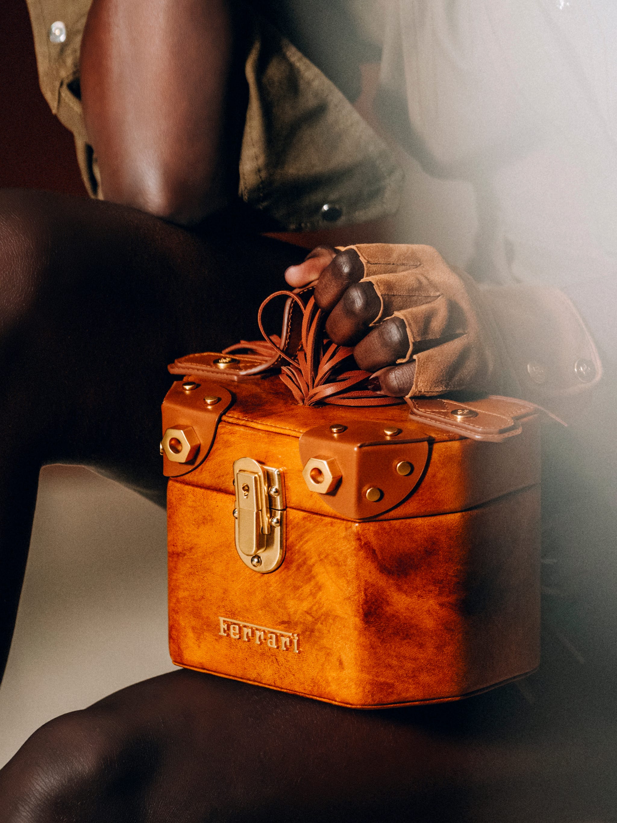 a model rests a burnished orange handbag on her lap