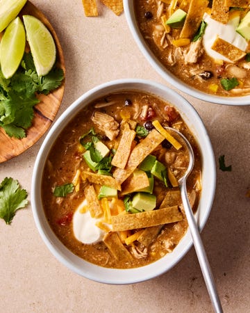 copycat chickfila chicken tortilla soup topped with tortilla strips, cilantro, avocado, and sour cream
