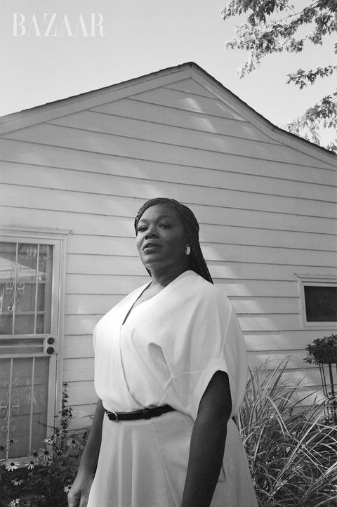 black and white portrait of cori bush in front of a house wearing a dress