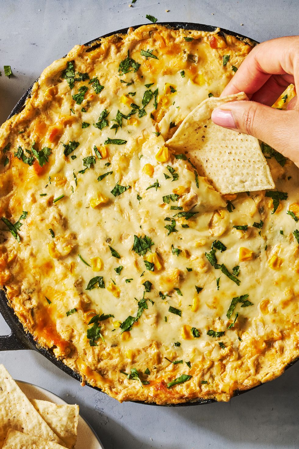 hot creamy corn dip in a cast iron skillet with tortilla chips