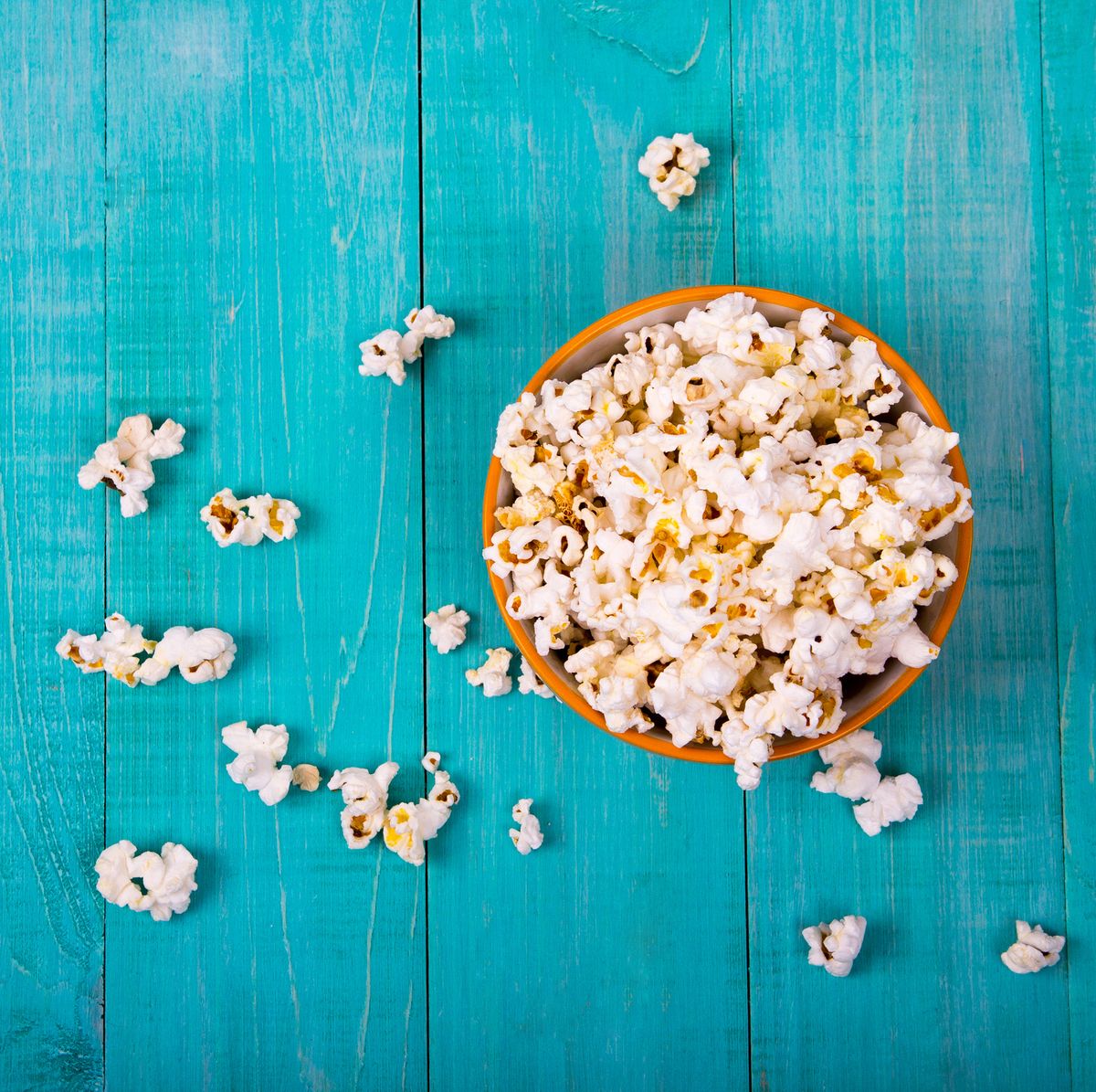 corn popcorn on a blue wooden background, as a snack for watching movies