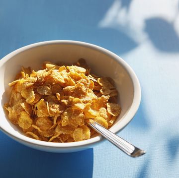 cornflakes and spoon in bowl, close up