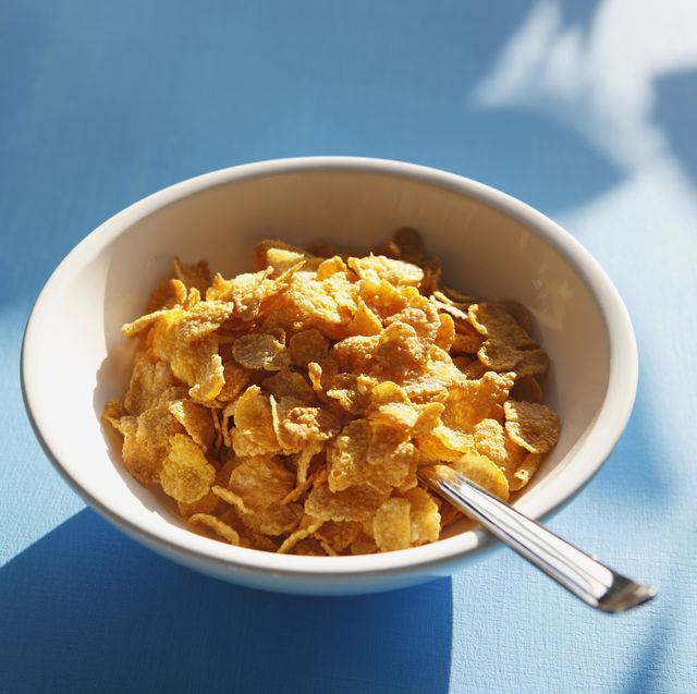 cornflakes and spoon in bowl, close up