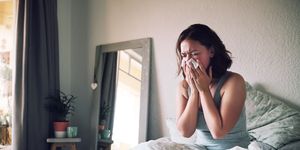 woman sneezing in bed with the flu