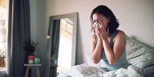 woman sneezing in bed with the flu