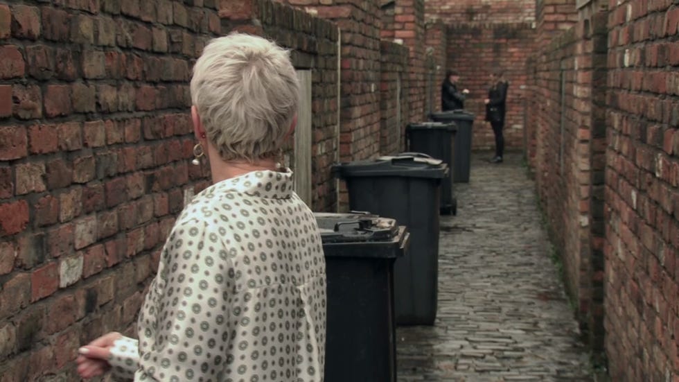 alleyway scene with three individuals and trash bins