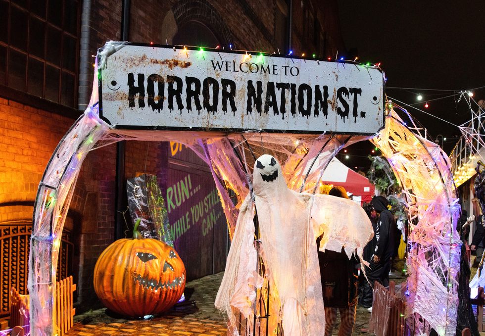 horror nation street sign with halloween decor of  ghosts and pumpkins