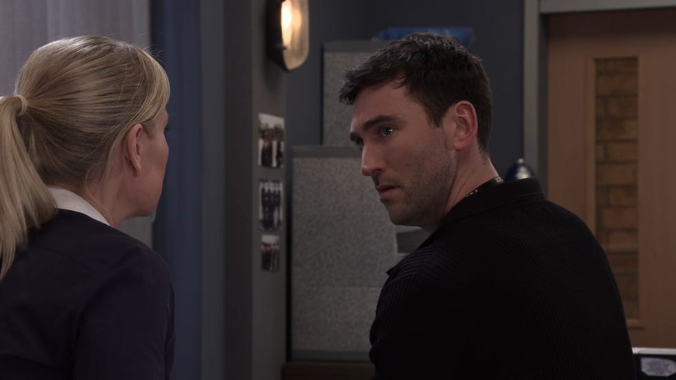 coronation street, kit green looking worried, in the police station in a black top