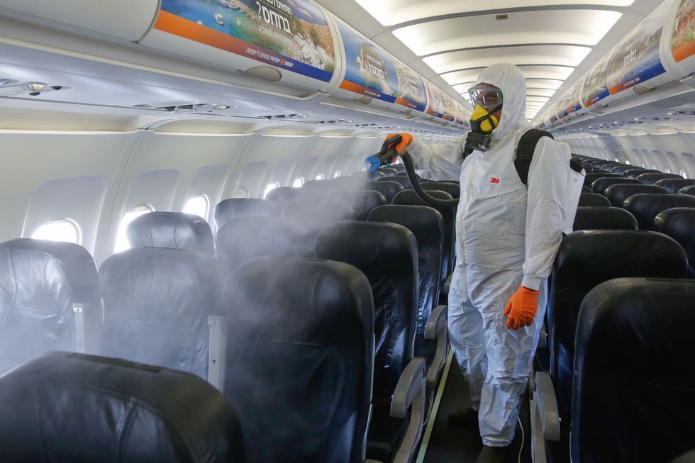 an israeli worker in full hazmat suit sprays disinfectant in the cabin of an israir airlines airbus a320 airplane, at the ben gurion international airport near the central israeli city of tel aviv, on june 14, 2020, amid the novel coronavirus pandemic photo by gil cohen magen  afp photo by gil cohen magenafp via getty images