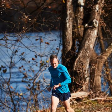 a man checking his watch while running on a trail by water